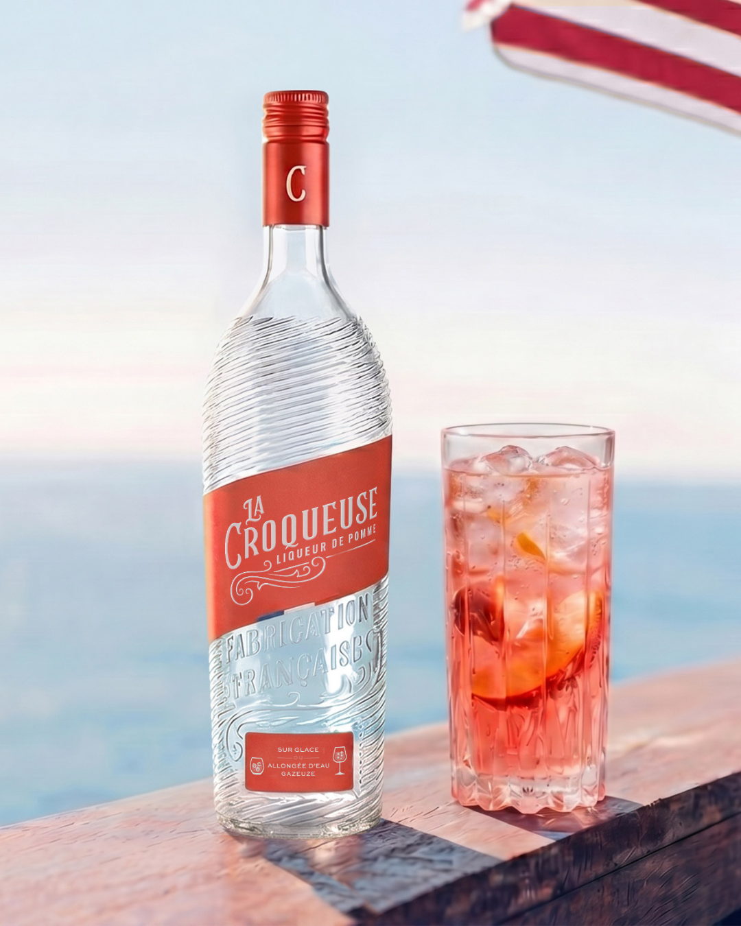 Bouteille La Croqueuse et cocktail rouge face à la mer